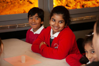 Children listening to an education presenter. They are smiling.
