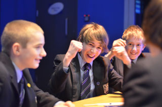 School children sat around a table, cheering.