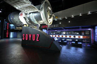 The Soyuz Module on display at the National Space Centre, seen side on with the café seating seen just behind.